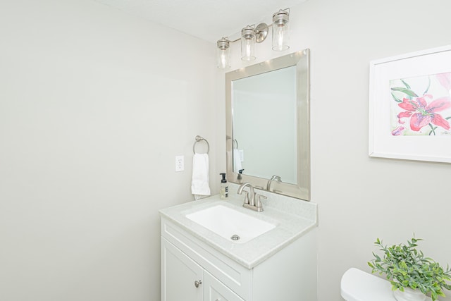 half bath featuring vanity and toilet