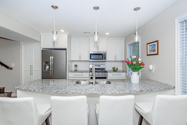 kitchen featuring appliances with stainless steel finishes, a sink, tasteful backsplash, a breakfast bar, and recessed lighting