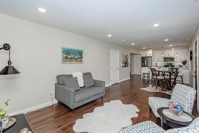 living area with baseboards, dark wood-type flooring, and recessed lighting