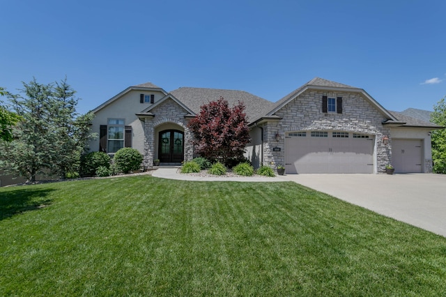french provincial home featuring french doors, stone siding, an attached garage, a front lawn, and driveway