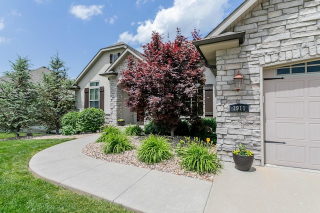 doorway to property with stone siding and a garage