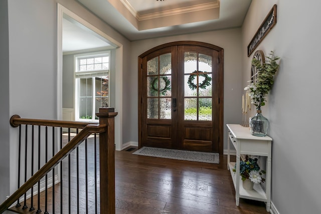 entrance foyer featuring ornamental molding, dark wood-style flooring, a raised ceiling, french doors, and baseboards