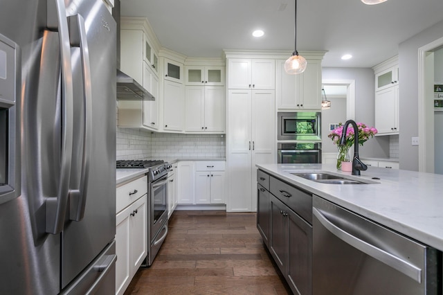 kitchen featuring stainless steel appliances, a sink, dark wood-style flooring, recessed lighting, and decorative light fixtures