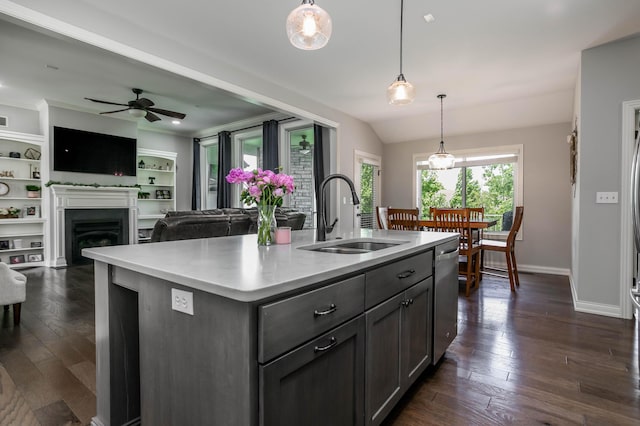 kitchen with a sink, a ceiling fan, dishwasher, dark wood-type flooring, and an island with sink