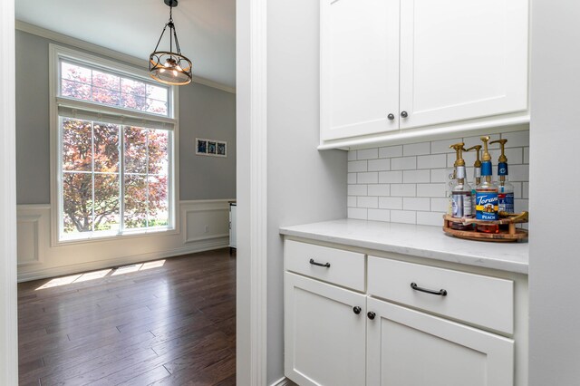 kitchen featuring white cabinetry, a wainscoted wall, pendant lighting, decorative backsplash, and dark wood-style flooring