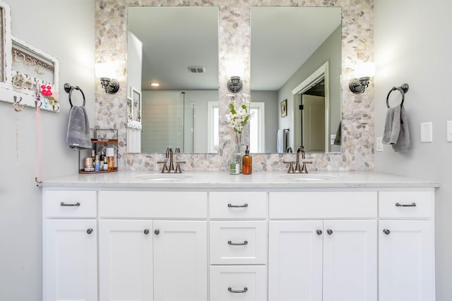 bathroom with tiled shower and double vanity
