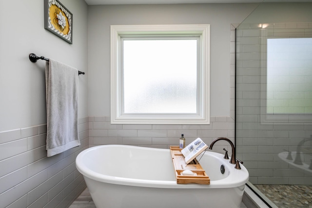 bathroom with tile walls, a freestanding bath, a shower stall, and a wainscoted wall