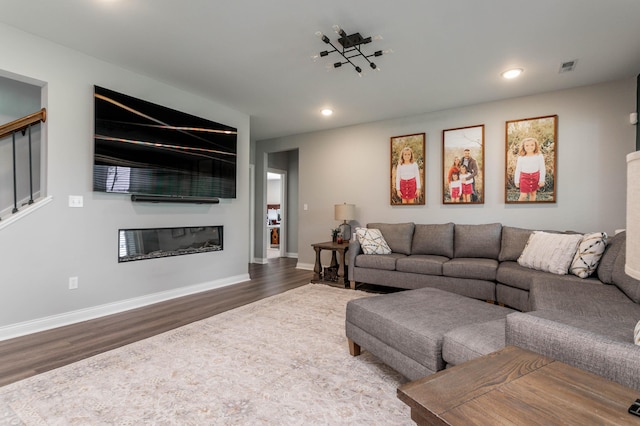 living room with wood finished floors, recessed lighting, a glass covered fireplace, baseboards, and stairway