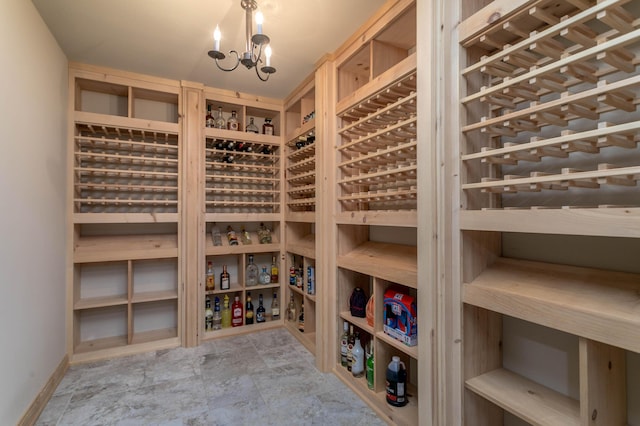 wine area with stone finish flooring, a chandelier, and baseboards