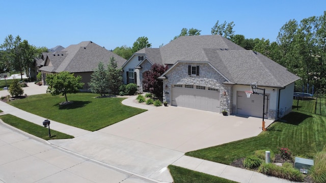 french country home with stone siding, a front yard, a garage, concrete driveway, and a trampoline