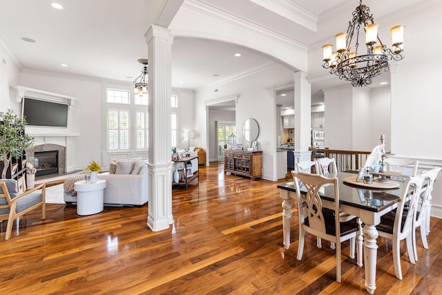4710 Winding Wood Ct, Columbia, MO 65203 - dining space featuring wood finished floors, a chandelier, a glass covered fireplace, decorative columns, and ornamental molding