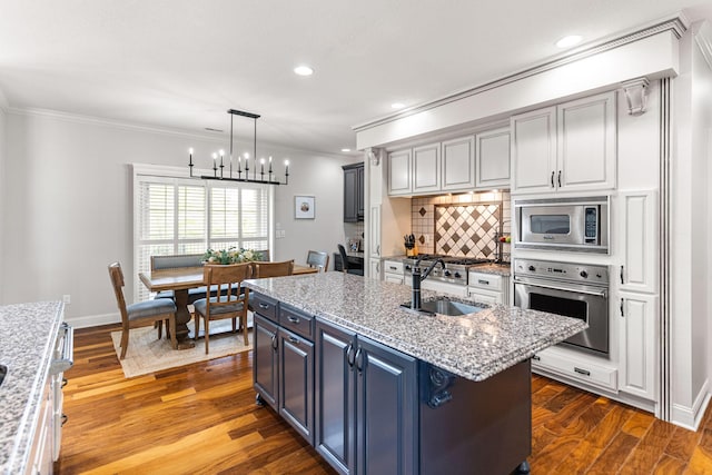 4710 Winding Wood Ct, Columbia, MO 65203 - kitchen featuring appliances with stainless steel finishes, crown molding, tasteful backsplash, an island with sink, and wood finished floors
