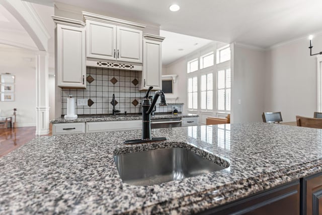 4710 Winding Wood Ct, Columbia, MO 65203 - kitchen with ornate columns, ornamental molding, dark stone counters, decorative backsplash, and arched walkways