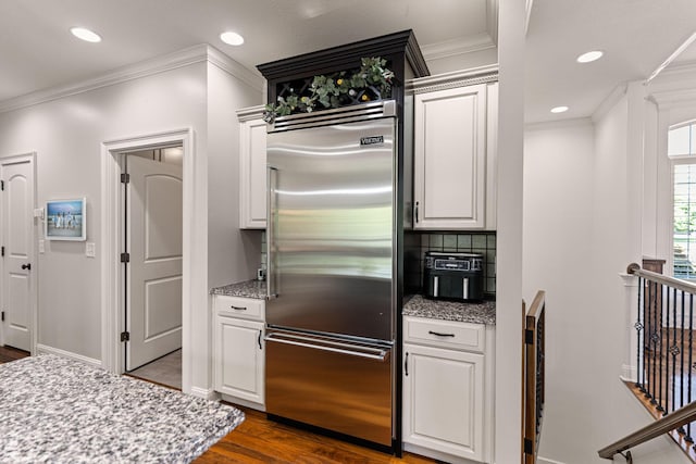 4710 Winding Wood Ct, Columbia, MO 65203 - kitchen featuring built in refrigerator, dark wood finished floors, ornamental molding, decorative backsplash, and white cabinets