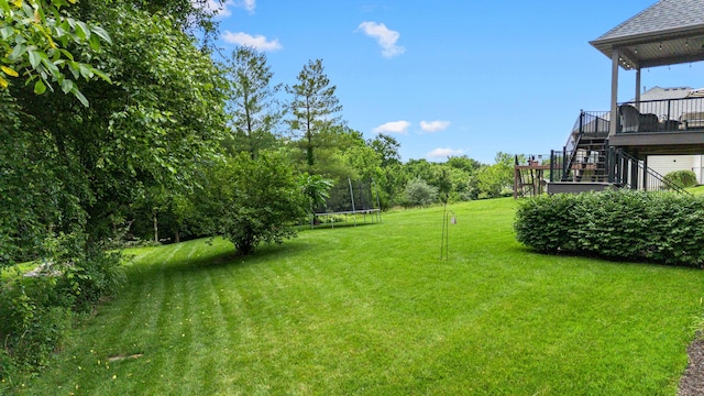 4710 Winding Wood Ct, Columbia, MO 65203 - view of green lawn featuring a trampoline, stairs, and a wooden deck
