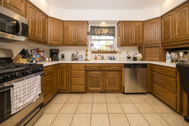 705 Redwood Dr, Ashland, MO 65010 - kitchen featuring stainless steel appliances, a sink, brown cabinets, light countertops, and light tile patterned floors