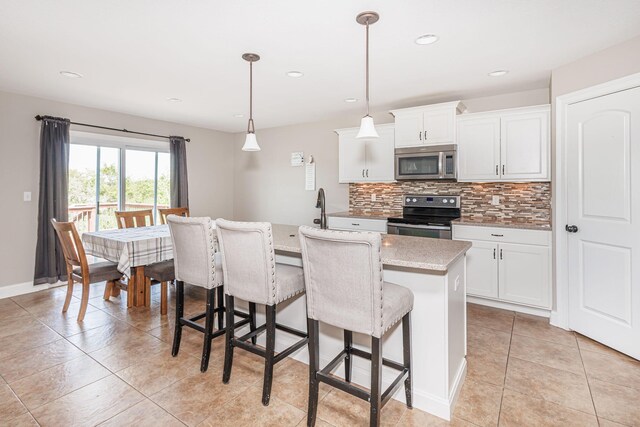 4105 Astoria Way, Columbia, MO 65203 - kitchen featuring appliances with stainless steel finishes, tasteful backsplash, an island with sink, a kitchen bar, and white cabinets