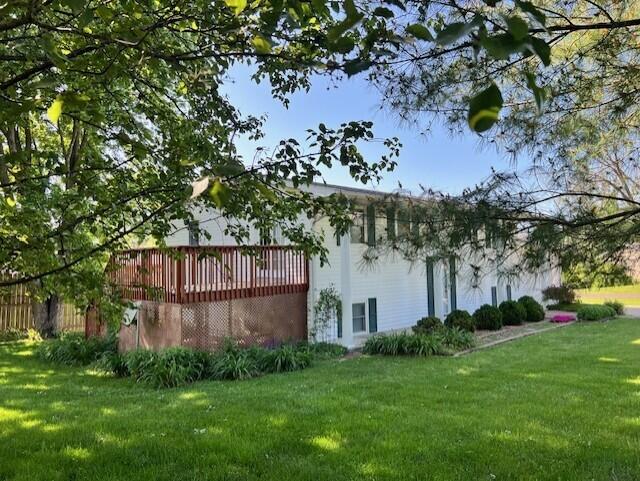 rear view of property featuring a yard and a wooden deck