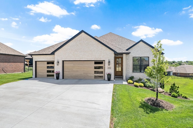 view of front of house featuring an attached garage, concrete driveway, a front lawn, and brick siding