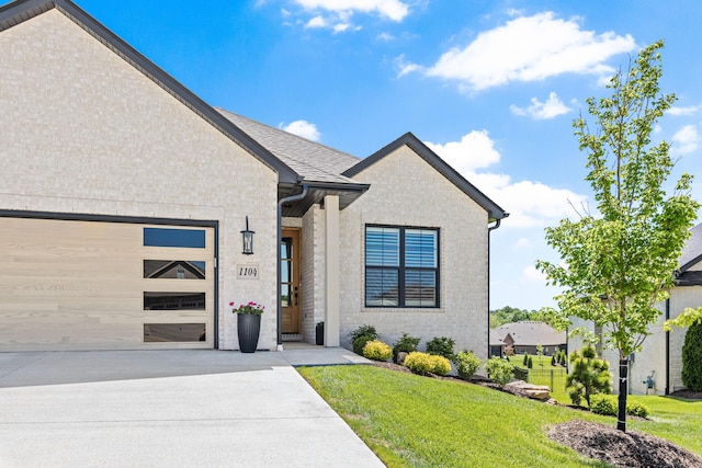 view of front of property featuring an attached garage, a front yard, and concrete driveway