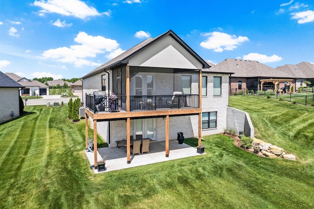 back of house with a patio area, a yard, brick siding, a deck, and a residential view