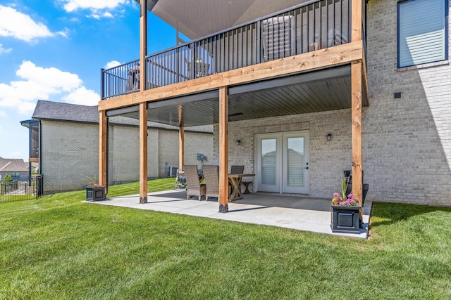 rear view of property featuring brick siding, french doors, a patio area, and a wooden deck