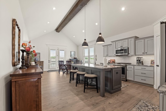 1104 Caymus Ct, Columbia, MO 65201 - kitchen featuring stainless steel appliances, beamed ceiling, gray cabinets, a kitchen bar, and decorative backsplash