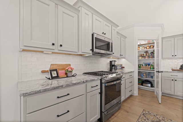 1104 Caymus Ct, Columbia, MO 65201 - kitchen with appliances with stainless steel finishes, light wood-style flooring, decorative backsplash, and light stone counters