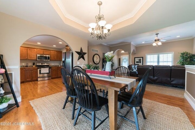 1200 Choctaw Ridge Dr, Holts Summit, MO 65043 - dining space featuring arched walkways, a raised ceiling, a chandelier, light wood-style flooring, and a ceiling fan
