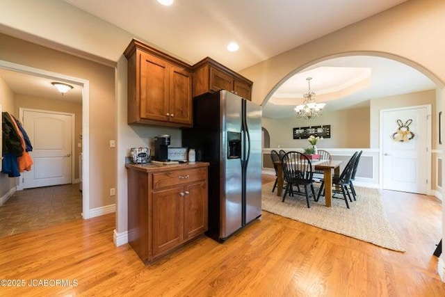 1200 Choctaw Ridge Dr, Holts Summit, MO 65043 - kitchen featuring arched walkways, stainless steel fridge, brown cabinetry, light wood-style floors, and a chandelier