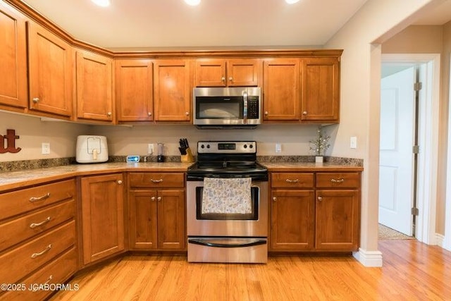 1200 Choctaw Ridge Dr, Holts Summit, MO 65043 - kitchen featuring stainless steel appliances, light wood-style floors, brown cabinetry, and light countertops