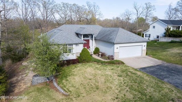 view of front of home with asphalt driveway, an attached garage, a front lawn, and a shingled roof