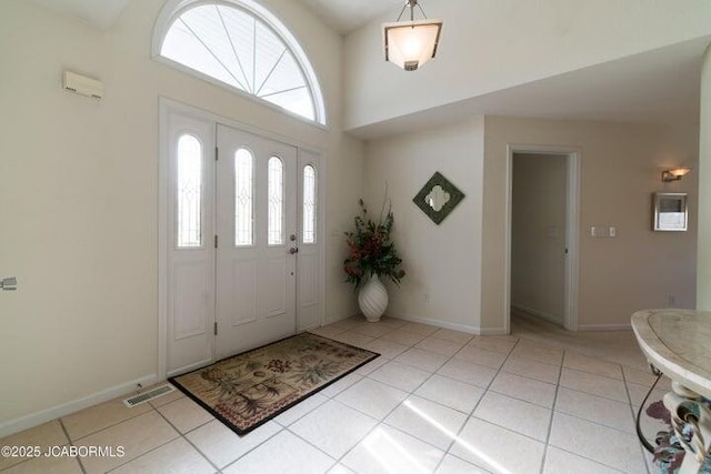 entrance foyer featuring light tile patterned floors, a high ceiling, and baseboards