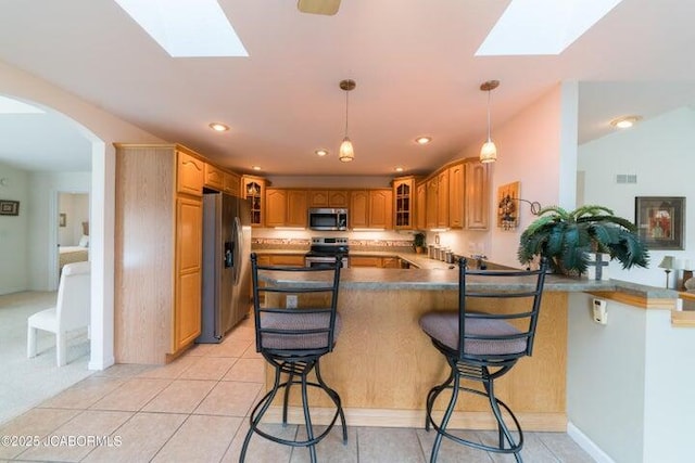 kitchen with stainless steel appliances, a skylight, a peninsula, glass insert cabinets, and recessed lighting