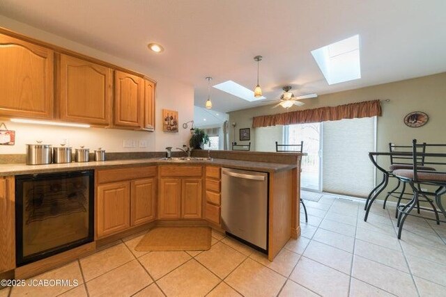 kitchen featuring dishwasher, a skylight, a sink, light tile patterned flooring, and recessed lighting
