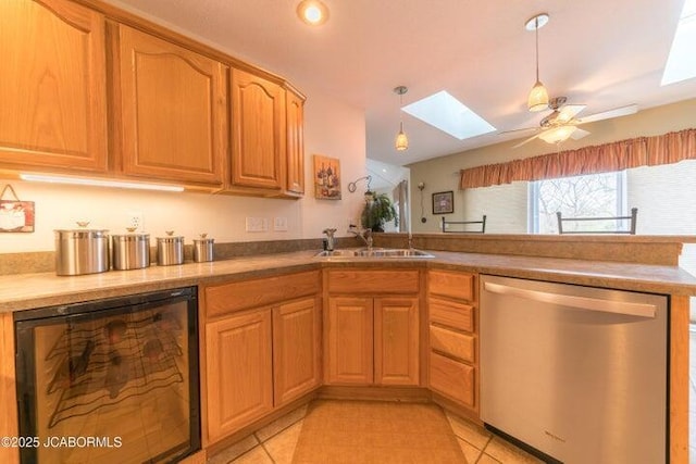 kitchen featuring dishwasher, a skylight, a peninsula, a sink, and ceiling fan
