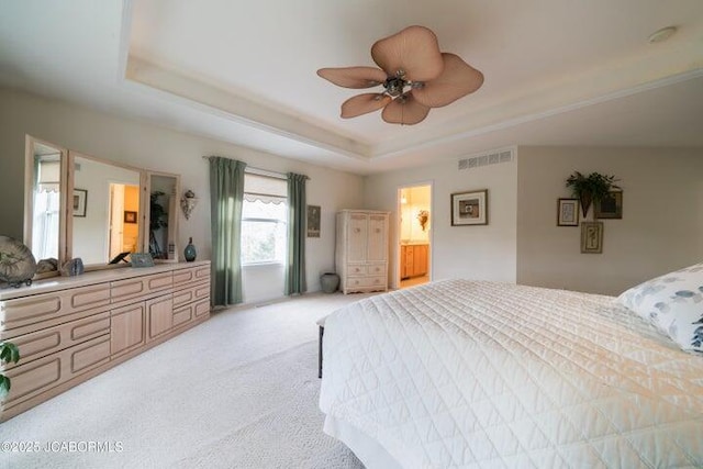 bedroom featuring a raised ceiling, light carpet, and a ceiling fan