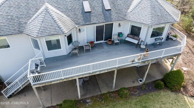 back of property featuring a deck, stairway, and roof with shingles