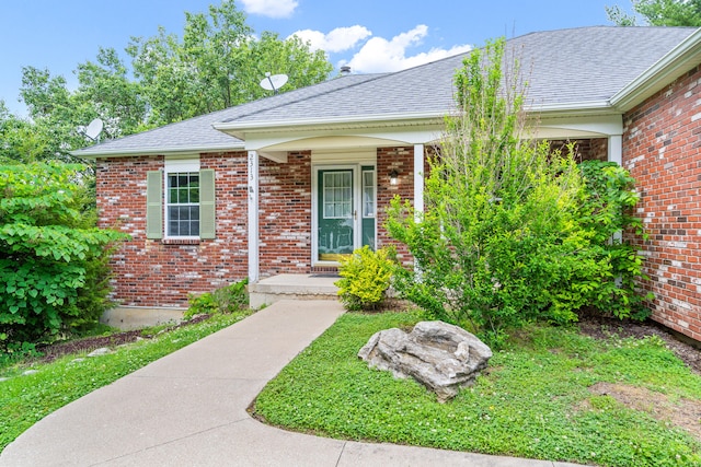 2313 Katy Ln, Columbia, MO 65203 - view of exterior entry featuring a porch, brick siding, and a shingled roof