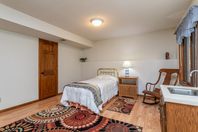 2512 Cimarron Dr, Columbia, MO 65203 - bedroom featuring a sink, light wood-style flooring, baseboards, and a textured ceiling