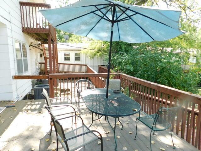wooden terrace with outdoor dining space and cooling unit