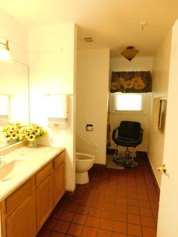 bathroom with toilet, double vanity, and tile patterned floors