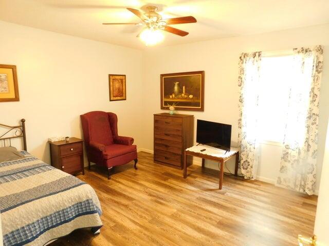 bedroom with light wood-style flooring, baseboards, and ceiling fan