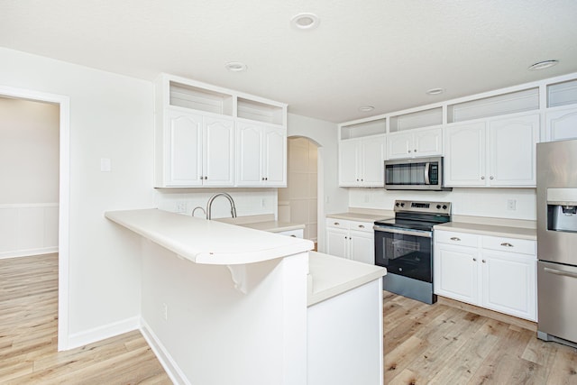 1050 Azoros Dr, Columbia, MO 65203 - kitchen with appliances with stainless steel finishes, light wood-style flooring, arched walkways, white cabinetry, and recessed lighting