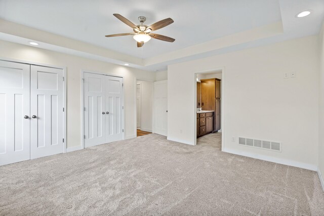 5111 Democracy Dr, Ashland, MO 65010 - unfurnished bedroom with light colored carpet, multiple closets, a tray ceiling, baseboards, and recessed lighting