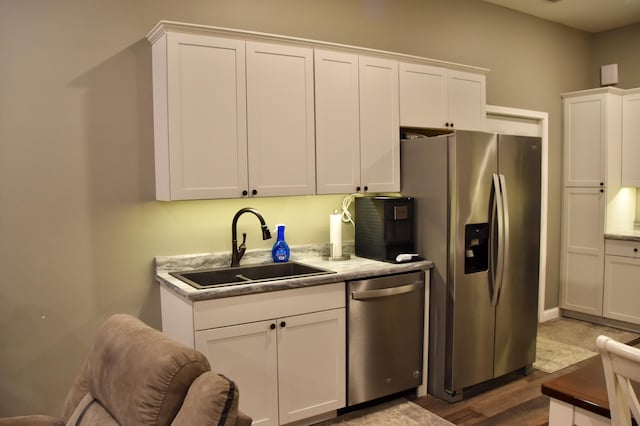 5100 E Dunbar Ln, Centralia, MO 65240 - kitchen with appliances with stainless steel finishes, a sink, white cabinetry, and wood finished floors
