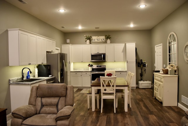 5100 E Dunbar Ln, Centralia, MO 65240 - kitchen with appliances with stainless steel finishes, a sink, white cabinets, dark wood-style flooring, and recessed lighting