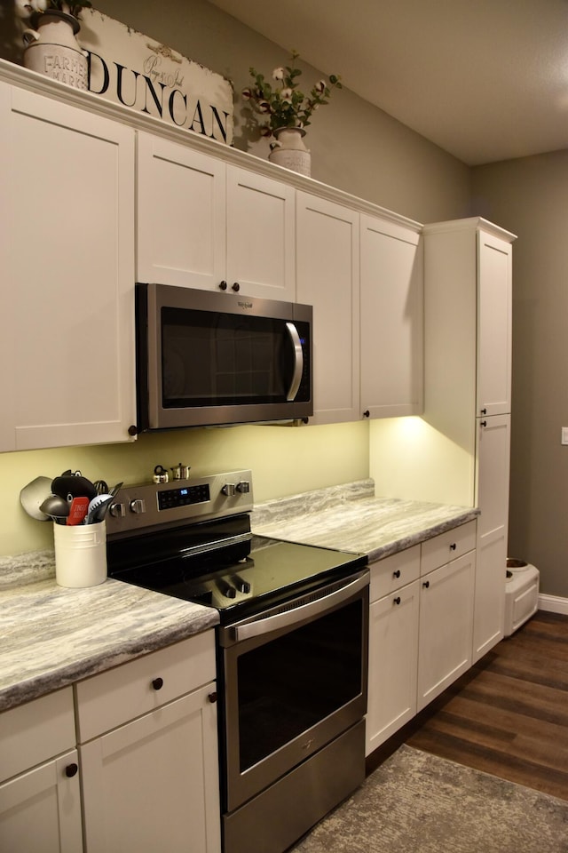 5100 E Dunbar Ln, Centralia, MO 65240 - kitchen featuring appliances with stainless steel finishes, white cabinetry, dark wood finished floors, and light stone countertops