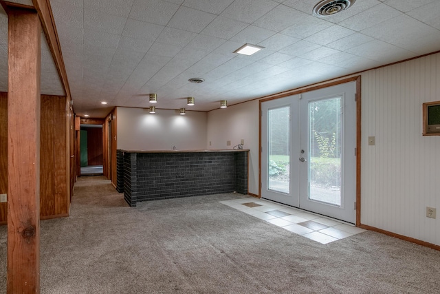1804 N Pin Oak Blvd, Columbia, MO 65202 - unfurnished living room featuring carpet, french doors, baseboards, wooden walls, and bar area