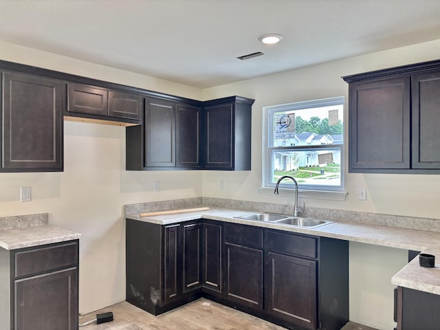 2505 Nest Ct, Columbia, MO 65202 - kitchen with a sink, light countertops, light wood finished floors, and dark brown cabinetry